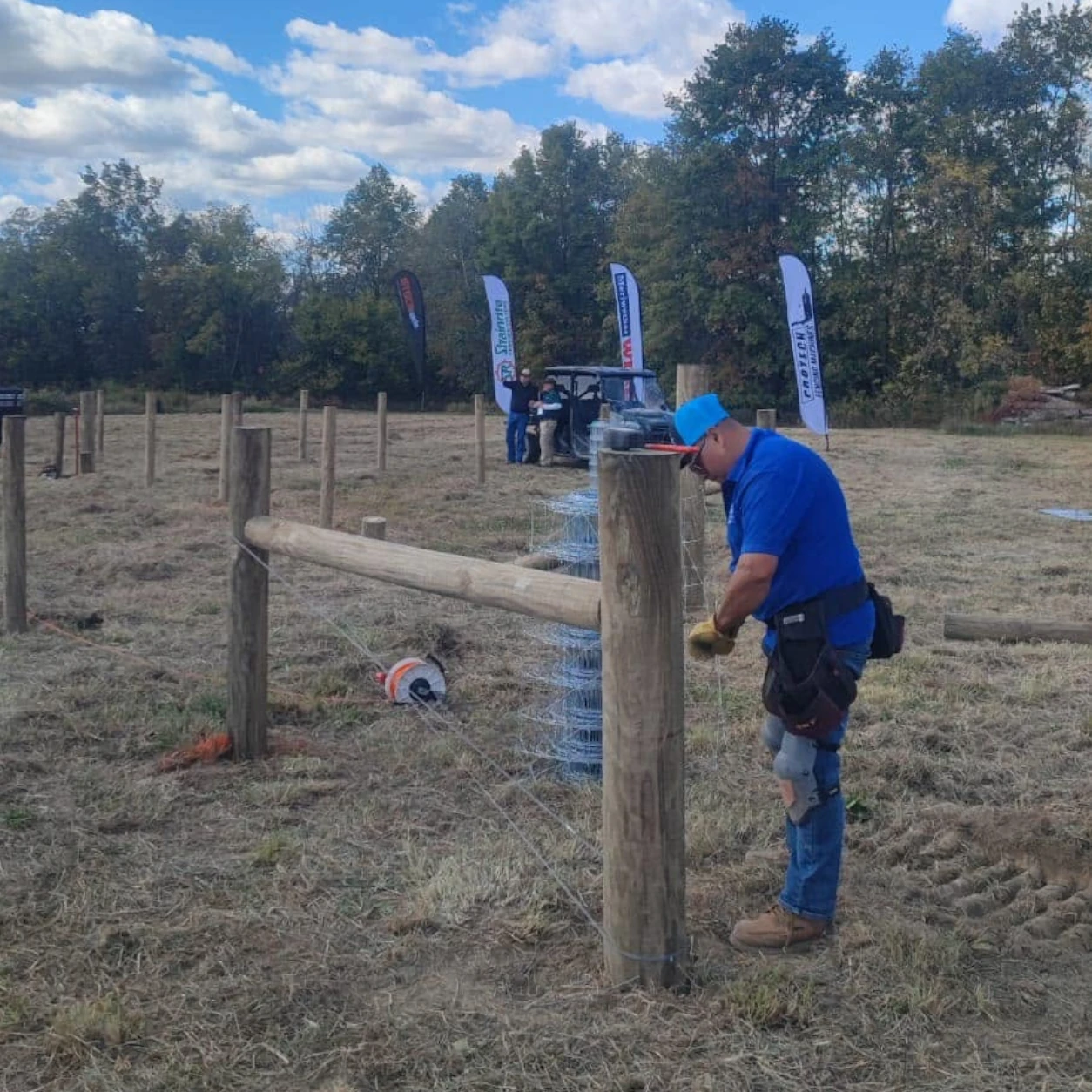 Contractor installing posts for cattle fencing on agricultural land