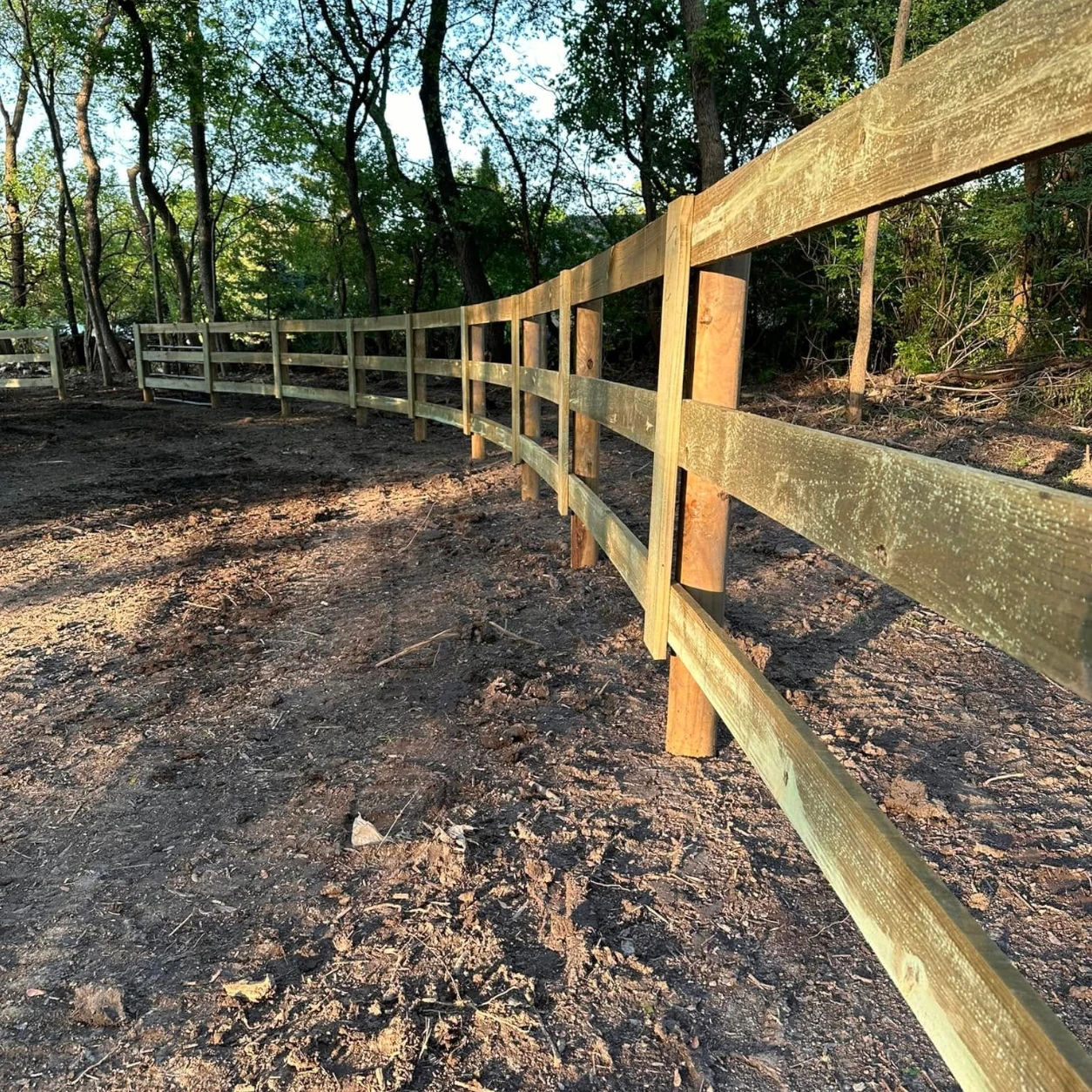 Newly installed wood board fence surrounding a rural paddock