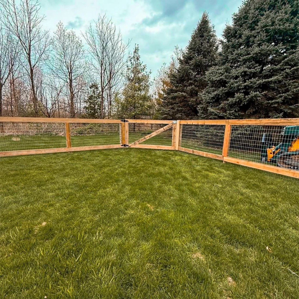 Wood-post and wire dog fencing enclosing a large grassy yard