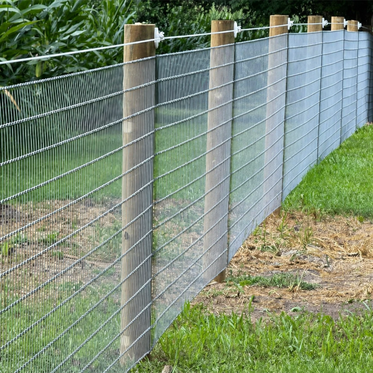 Woven wire fencing installed with wooden posts along a rural property